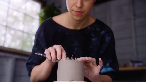 Potter-shaves-flakes-off-of-pot-on-pottery-wheel