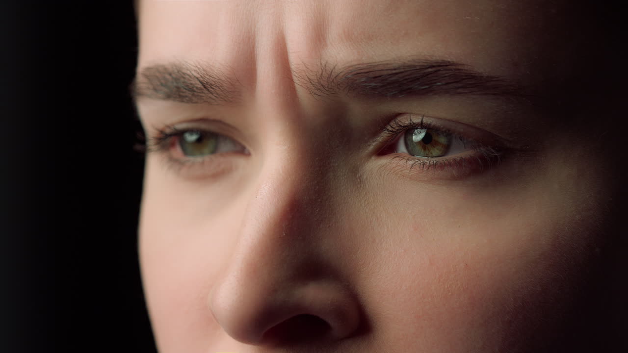 슬픈 여성 얼굴의 매크로 실내에서 불쾌한 비디오를 보는 여성 얼굴을 만드는