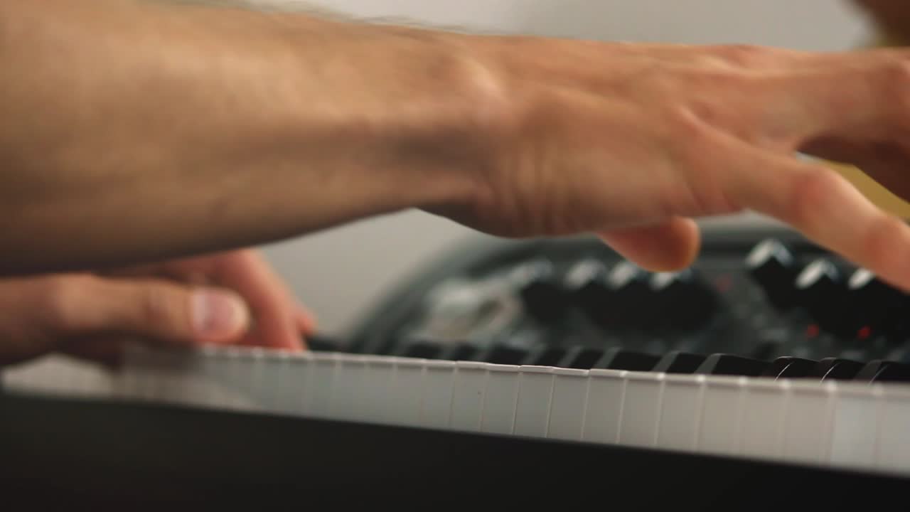 primer plano de un pianista profesional y teclas de pianos de escenario mientras toca acordes durante una sesión de grabación con un fondo brillante
