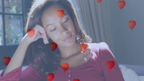 animation of digital heart icons over woman smiling at home