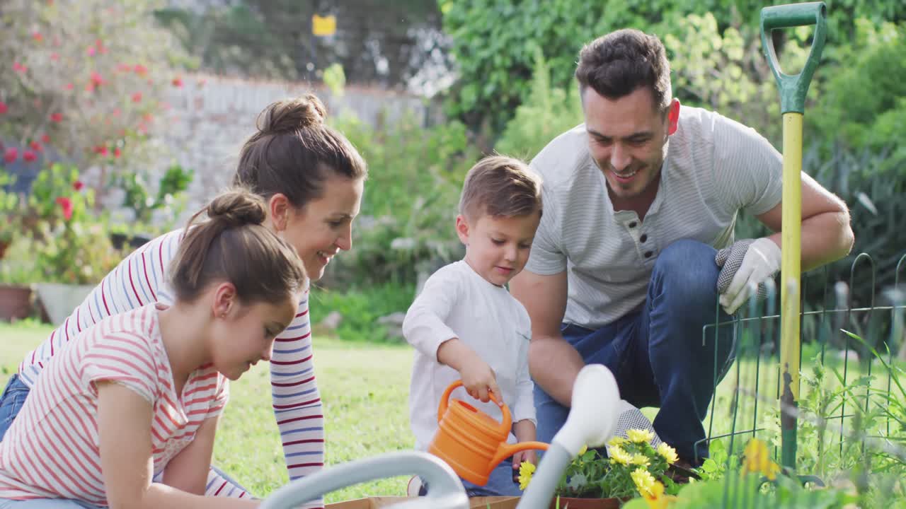 familia caucásica feliz jardinería y riego de plantas juntos