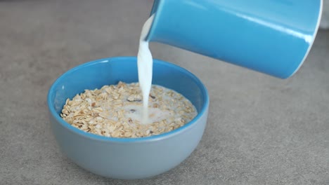 pouring milk in oats flakes in a bowl