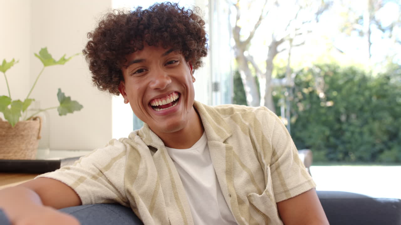 Smiling young man sitting on couch, enjoying time with friends indoors, at home