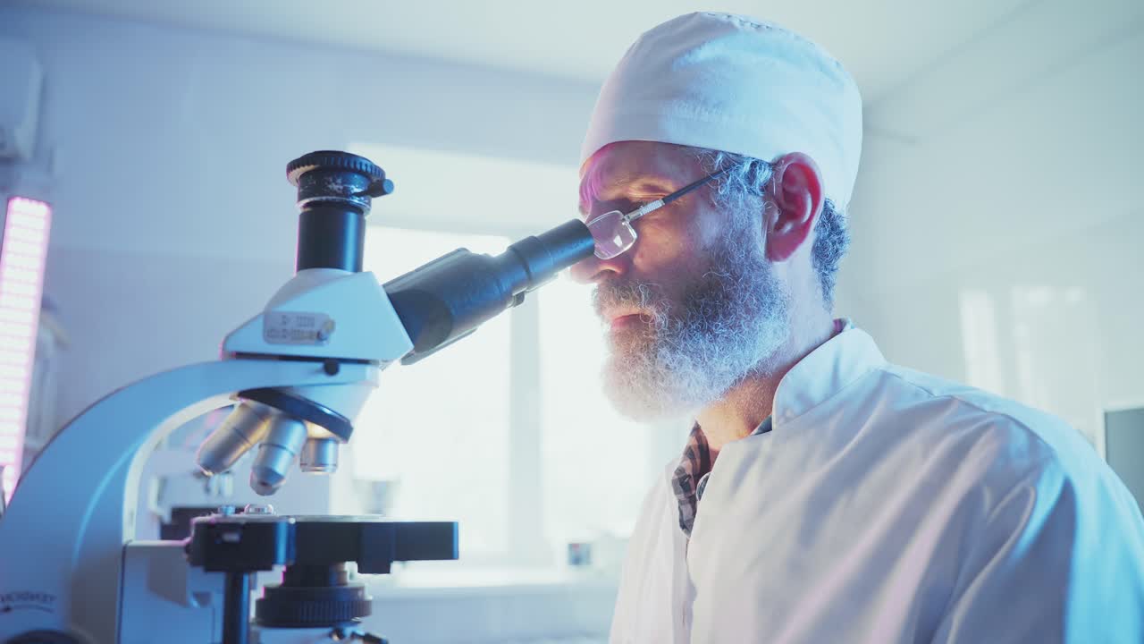 Focused Scientist Looking Through Microscope in Modern Laboratory