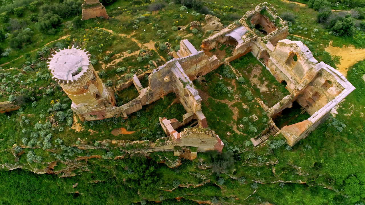 vista aérea de pájaro sobre las ruinas de un edificio antiguo en la cima de una colina rodeada de vegetación verde en el norte de troina, sicilia, italia durante el día