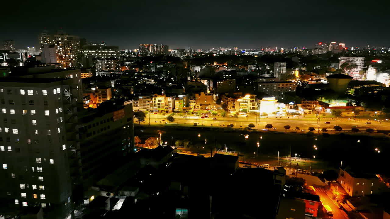 Soar above a vibrant night highway glowing with city lights, tracing the serene river's edge. Perfect for urban, travel, or cinematic projects