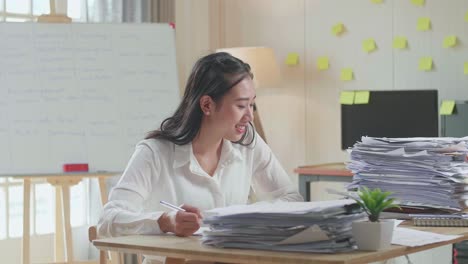 smiling asian woman enjoys working with documents at the office