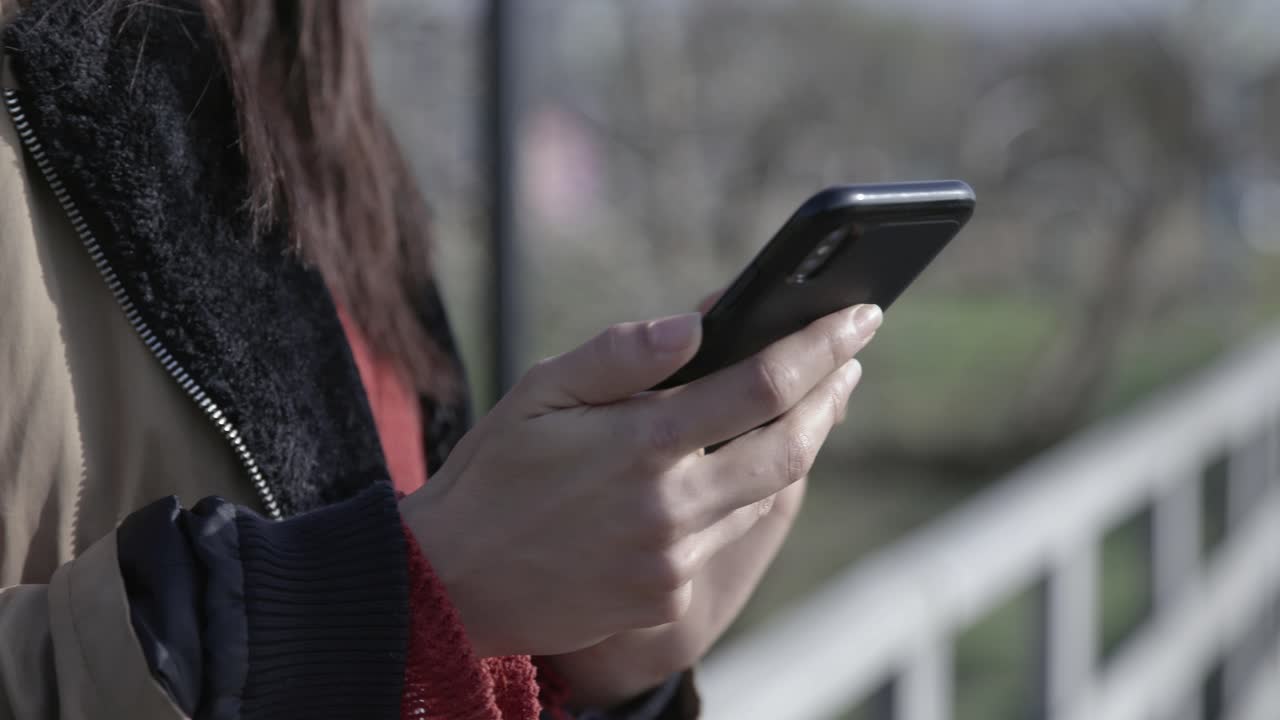 Close Up of Person's Hands Using a Smartphone Outdoors