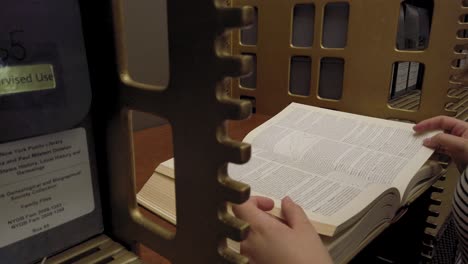 close up of female hands on open history book in public library of new york usa