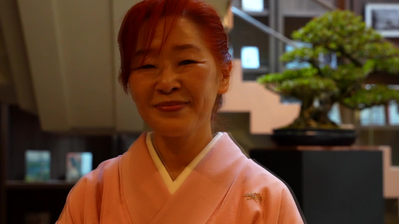 Donna giapponese sorridente in un kimono tradizionale che guarda in camera durante una cerimonia del tè.