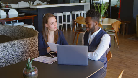 front view of young cool mixed-race business team planning and sitting at table of modern office 4k