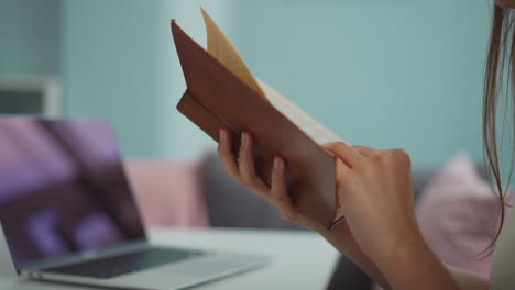 estudiante de sexo femenino sostiene un libro volviendo páginas para encontrar información