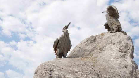 Stone-resort-jetty-promenade-cormorant-bird-sculptures-at-Morecambe-beach-under-blue-sky-slow-right-dolly