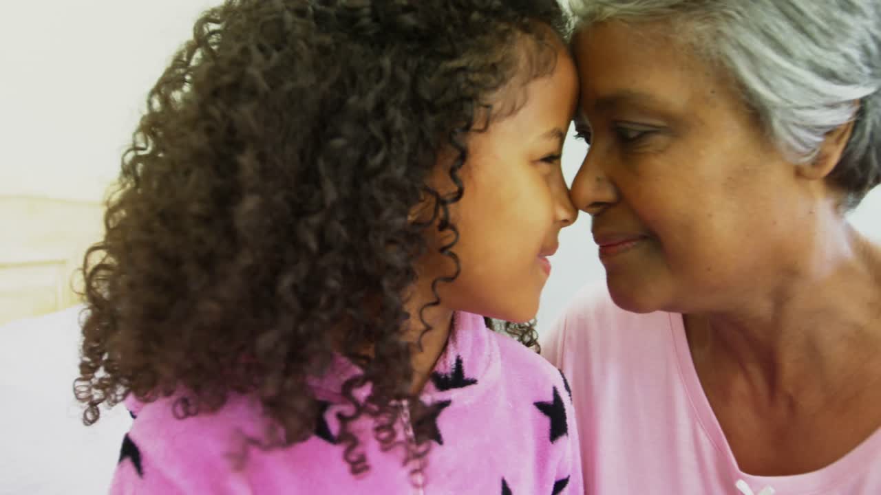 nieta sonriente y abuela frotando las narices en la cama 4k
