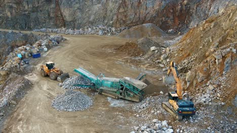 powerful machinery in action: an aerial view of an excavator, tracked incline screener, and wheel loader at work