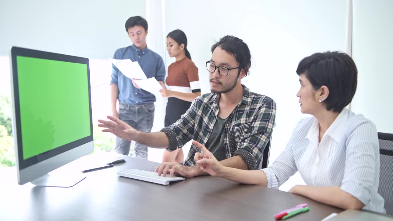 소규모 스타트업 그룹 토론실에서 젊은 아시아 남자가 그린 스크린 컴퓨터에서 자신의 아이디어를 팀에 발표합니다.