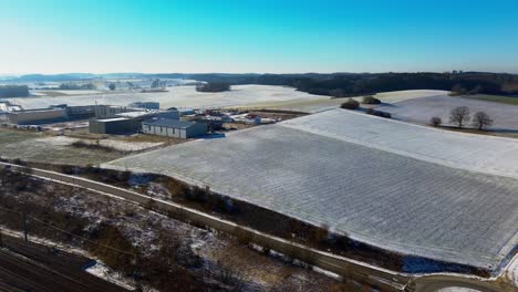 Frostiger-Industriepark-Neben-Schneebedeckten-Feldern-Im-Wintersonnenlicht