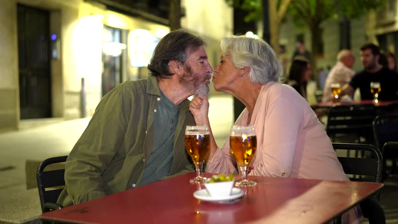 Affectionate Senior Couple Enjoying Drinks at an Outdoor Cafe