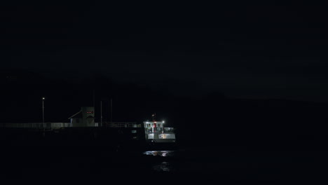 ferry boat waiting at pier at night, distant static shot