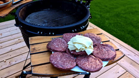 hamburger patties and cheese slices prepared for grilling at an outdoor barbecue