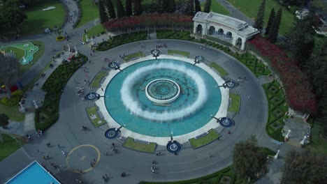 drone orbits around a circular water fountain