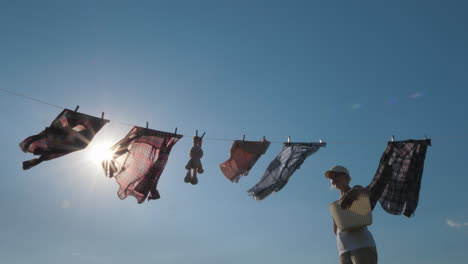 a woman with a basket looks like hanging wet clothes on a rope 4k video