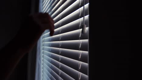 hombre mirando a través de las persianas de la ventana después de despertar