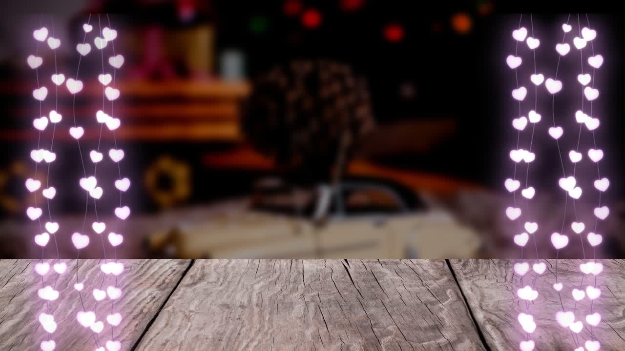 animación de luces de hadas en forma de corazón colgando sobre una tabla de madera contra una casa de navidad decorada