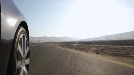 car wheel perspective, passes over white and yellow zebra crossing and speeds off into the desert