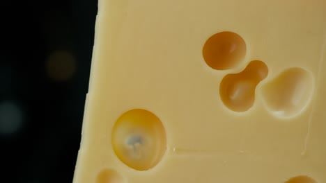 close up part of medium hard cheese head edam gouda parmesan on wooden board, with nuts and grapes rotaiting on the plate