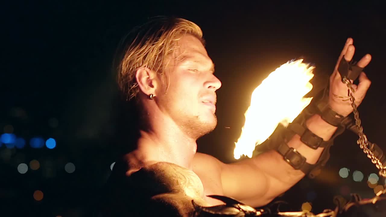 Young blond male spins two burning pois Slow motion shot Close-up