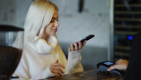 en el café la mujer paga por teléfono móvil sin contacto con el sistema de tarjeta de crédito