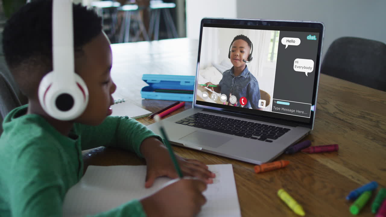 Schoolboy using laptop for online lesson at home, with his colleague and web chat on screen