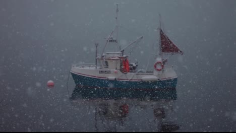 Still-shot-of-a-small-boat-during-a-snow-storm-in-the-middle-of-the-ocean,-anchored-ship-waiting-for-the-storm-to-pass