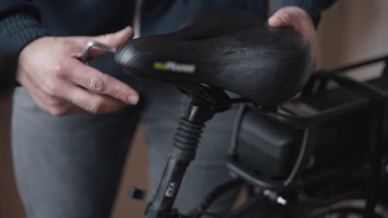 남성 자전거 정비사가 새 전기 자전거의 좌석을 조정하여 고객을 위해 준비합니다.