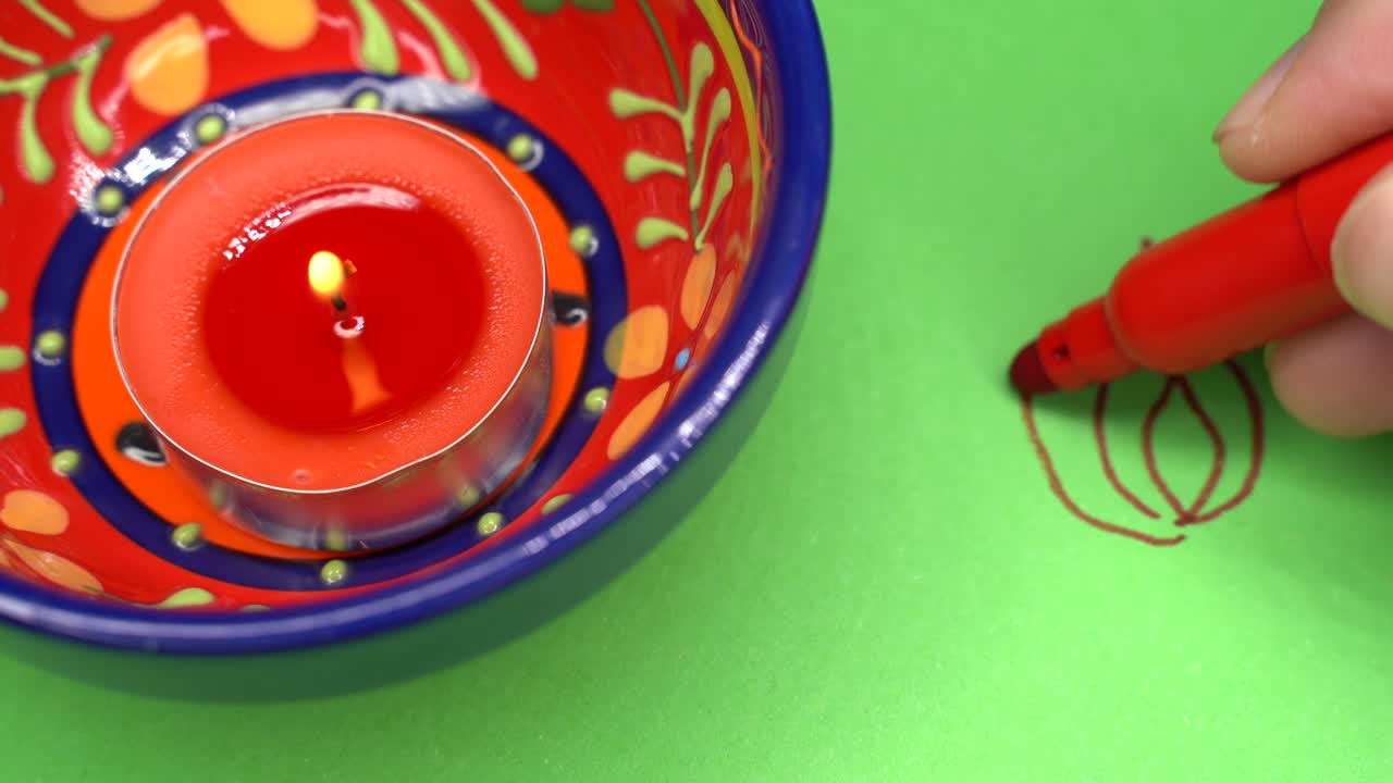 Hand drawing of a Diwali rangoli on paper with a Diwali candle light.