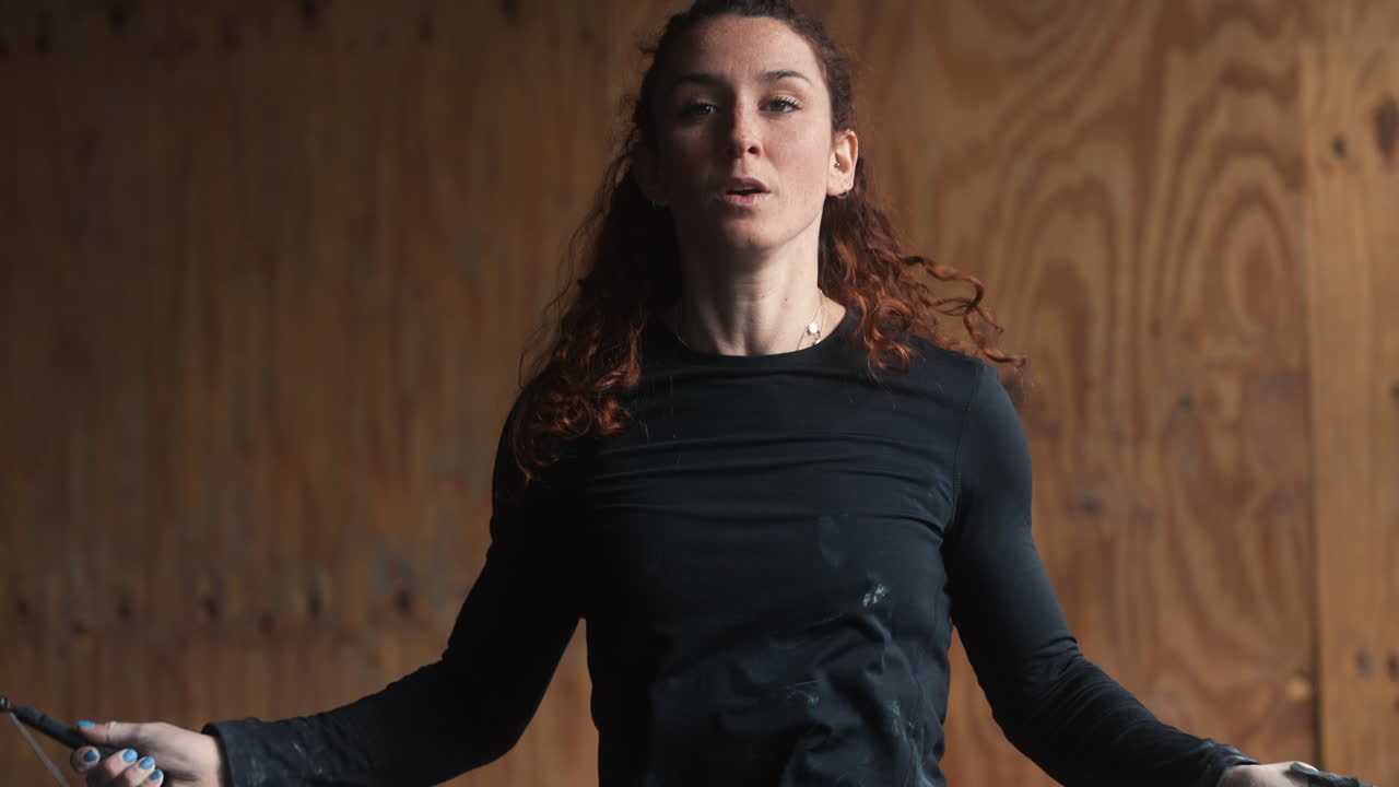 mujer pelirroja fuerte saltando con una cuerda de salto comenzando un entrenamiento dinámico