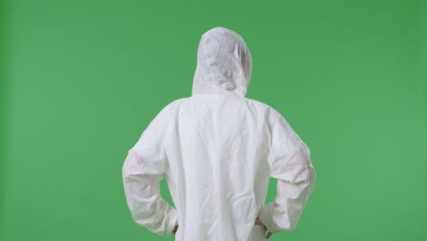 back view of asian male scientist putting hands on his hip and looking around on green screen background