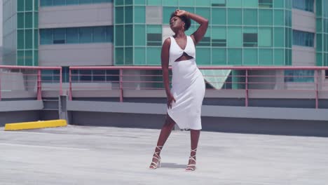 On-a-rooftop,-a-black-girl-in-a-white-dress-looks-out-at-the-city