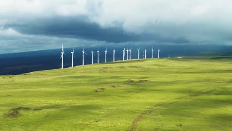 Wind-turbines-at-South-Point-Park-in-cloudy-Hawaii,-slow-aerial-pan