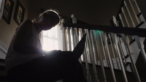 Sunlit-Woman-Uses-Tablet-on-Stairs