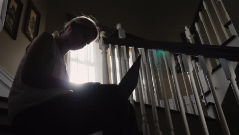 mujer iluminada por el sol usa una tableta en las escaleras