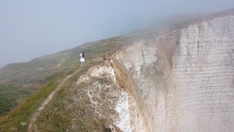 mujer en un acantilado en tiempo de niebla