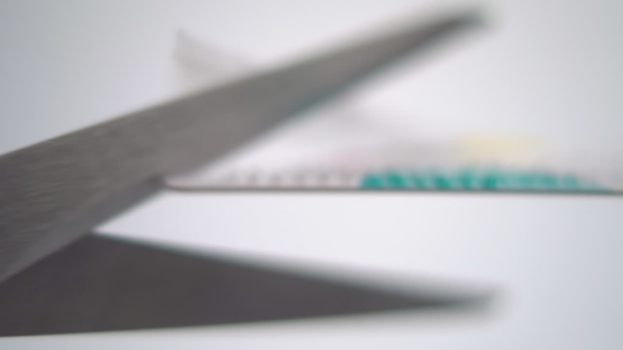 Cutting bank credit card with scissors on white background. Bankruptcy and loss of finance conceptual view. Macro