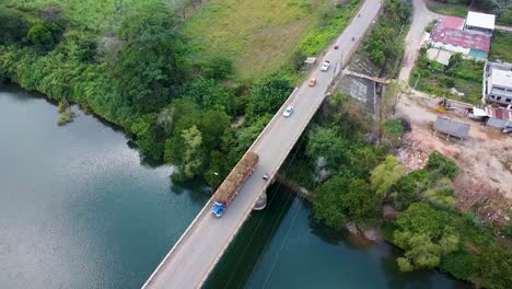 lorry carrying hay bails driving on bridge over cyan river