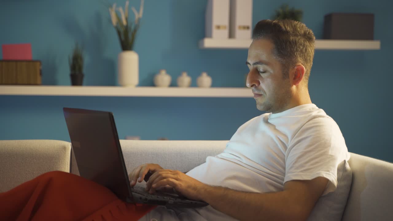 hombre infeliz usando una computadora portátil acostado.