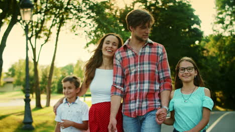 familia positiva caminando por la calle. niños alegres y padres riendo al aire libre