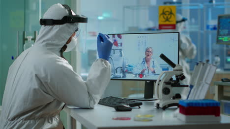 senior woman doctor offering medical online advices to chemist in ppe suit