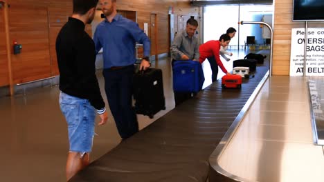 commuters taking their baggage from baggage carousel