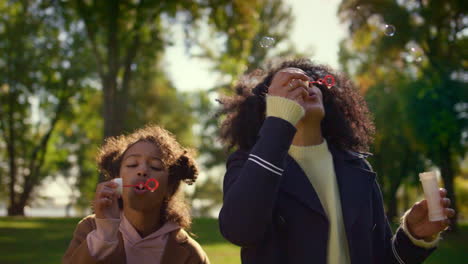 Parent-kid-blowing-soap-colorful-bubbles-in-green-sunny-park-together-portrait.